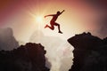 Silhouette of young man jumping over mountains and cliffs at sunset