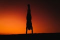 silhouette of young man in a park doing yoga sport. orange sky background. healthy lifestyle