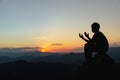 Silhouette of a young man praying to God on the mountain at sunset background. Woman raising his hands in worship. Christian Royalty Free Stock Photo