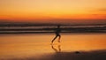Silhouette of young man runs along the beach during amazing sunset. Royalty Free Stock Photo
