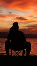 Silhouette of a young man sitting by the lake enjoying the sunset Royalty Free Stock Photo