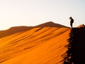 Silhouette of young man standing on the red dune ridge in Sossusvlei, Namib Desert, Namibia, Africa