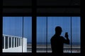 Silhouette of a young man taking a picture in the airport through a window. Travel concept Royalty Free Stock Photo