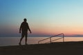 Silhouette of a young man walking along the embankment at sunset Royalty Free Stock Photo