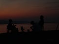 Silhouette of young men sitting by the lake enjoying the sunset Royalty Free Stock Photo