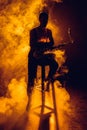 silhouette of young musician sitting on stool and holding saxophone