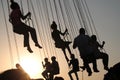 Silhouette of young people on Ferris wheel and swinging carousel in stop motion on sunset background