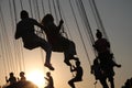 Silhouette of young people on Ferris wheel and swinging carousel in stop motion on sunset background