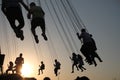 Silhouette of young people on Ferris wheel and swinging carousel in stop motion on sunset background