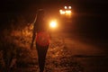 Silhouette of young slender woman in the backlight of car headlights on the road Royalty Free Stock Photo