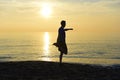 Silhouette of young sport man stretching leg after running workout outdoors on beach at sunset Royalty Free Stock Photo