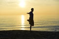 Silhouette of young sport man stretching leg after running workout outdoors on beach at sunset Royalty Free Stock Photo