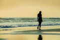 Silhouette of young sporty woman walking on seashore after running workout at a beautiful beach enjoying sunset light and relax in Royalty Free Stock Photo