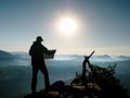 Silhouette of young tourist guide looking in paper map