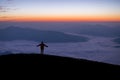 Silhouette of young traveler standing alone on top of the mountain and watched beautiful view of foggy landscape and sunrise in Royalty Free Stock Photo