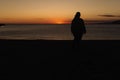 Silhouette of a young woman alone watching the sea during the sunset