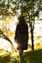 Silhouette of a young woman ascending on hill at sunset, figure girl in the autumn landscape in a dress