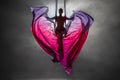 Silhouette of a young woman balancing on an airy silk ribbon and waving a cloth like butterfly wings. A female athlete Royalty Free Stock Photo