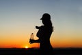 Young woman with bottle water after jogging on the sunset backgrounds. Top view on the city