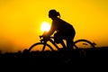 Silhouette of young woman cyclist on sunset