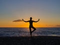Silhouette of young woman doing exercises on the sea beach during sunset. Yoga, fitness and a healthy lifestyle Royalty Free Stock Photo