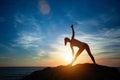 Silhouette of young woman doing exercises on the sea beach during sunset. Royalty Free Stock Photo