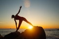 Silhouette of young woman doing fitness exercises on the beach at amazing sunset. Royalty Free Stock Photo