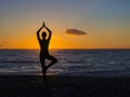 Silhouette of a young woman doing yoga on the beach at sunset. Royalty Free Stock Photo