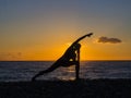 Silhouette of a young woman doing yoga on the beach at sunset. Royalty Free Stock Photo