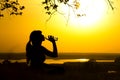 Silhouette of a woman drinking water after fitness training in nature, female profile at sunset, concept of sport and relaxation Royalty Free Stock Photo
