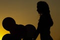 Silhouette of young woman with flying balloons against the sky. Royalty Free Stock Photo