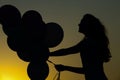 Silhouette of young woman with flying balloons against the sky. Royalty Free Stock Photo