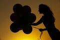 Silhouette of young woman with flying balloons against the sky. Royalty Free Stock Photo