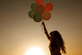 Silhouette of young woman with flying balloons against the sky. Royalty Free Stock Photo