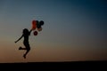 Silhouette of young woman with flying balloons against the sky. Royalty Free Stock Photo