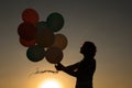 Silhouette of young woman with flying balloons against the sky. Royalty Free Stock Photo