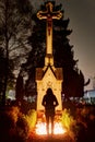 A silhouette of a young woman in front of a historic statue with a jesus on a cross at Vitkovice cemetery in Ostrava, CZ