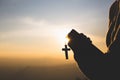 Silhouette of Young woman hands holding holy Bible and lift of christian cross, religion symbol in light and landscape over a Royalty Free Stock Photo