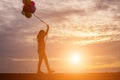 Silhouette of young woman holding colorful of balloons with sunset