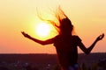 Silhouette Of Young Woman Holding Hands Up And Looking To The Sunset.