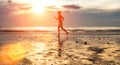 Silhouette of a young woman jogger at sunset on the seashore. Sport.