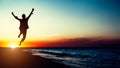 Silhouette young woman jumping with hands up on the beach at the sunset Royalty Free Stock Photo