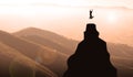 Silhouette of a young woman jumping on the top of the mountain celebrating Success.