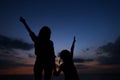Silhouette of young woman and little girl walking in vening, sunset background. Royalty Free Stock Photo