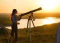 Silhouette of young woman looking view through the telescope at summer sunset Royalty Free Stock Photo