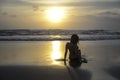 Silhouette of young woman lying on sand looking to sea sunset horizon with beautiful sun Royalty Free Stock Photo