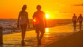 SILHOUETTE: Young woman and man walk along a scenic coastal promenade at sunset.