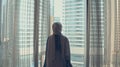 Silhouette of young woman opens curtains on the big window stretches arms and looking out her apartment on the city Royalty Free Stock Photo