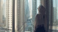 Silhouette of young woman opens curtains on the big window stretches arms and looking out her apartment on the city Royalty Free Stock Photo