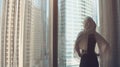 Silhouette of young woman opens curtains on the big window stretches arms and looking out her apartment on the city Royalty Free Stock Photo
